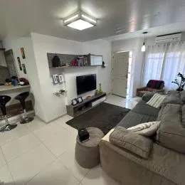 Sala de estar com televisão montada na parede e móveis baixos.