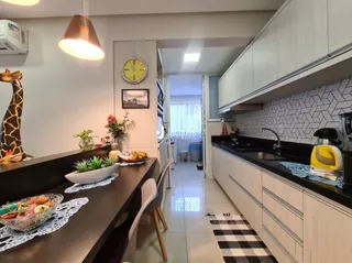 Uma cozinha moderna com armários brancos e bancadas escuras.