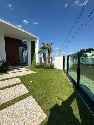 Fachada de uma residência moderna com jardim gramado e calçada de pedras.