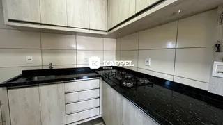 Cozinha moderna com armários claros e bancadas escuras.