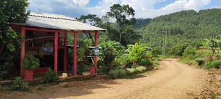 Foto da fachada de uma construção com telhado vermelho em uma área rural.