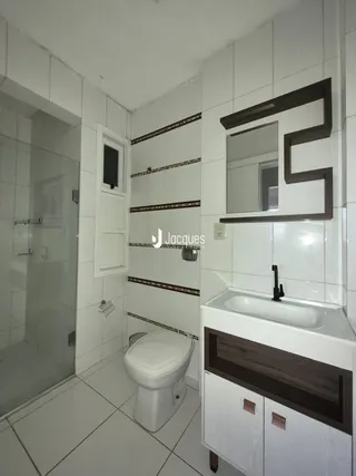 Foto de um banheiro com revestimento cerâmico branco e louças sanitárias.