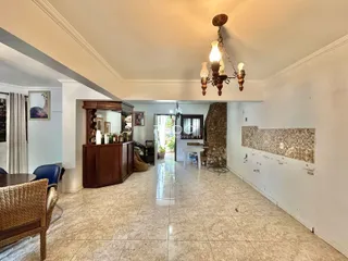 Uma sala de estar ampla com piso de cerâmica clara e iluminação central.