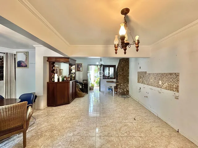 Uma sala de estar ampla com piso de cerâmica clara e iluminação central.