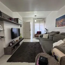 Foto interna de uma sala de estar com sofá e televisão.