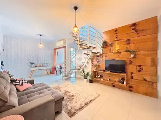 Sala de estar moderna com parede de madeira e escadaria de vidro.