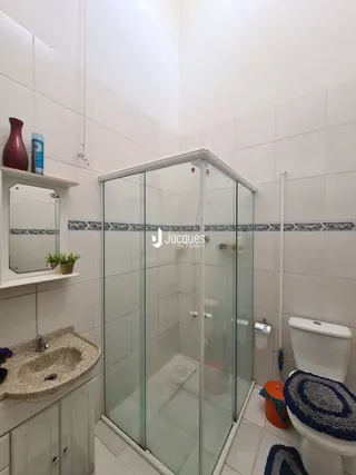 Foto de um banheiro com box de vidro e vaso sanitário.