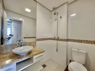 Banheiro com revestimento cerâmico e bancada de granito.