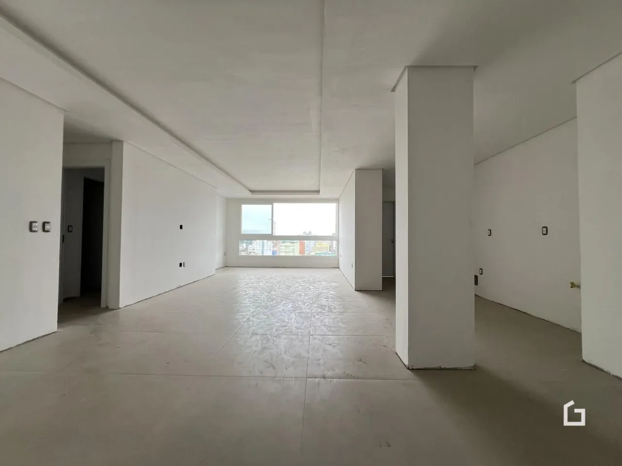 Corredor interno de um imóvel com paredes brancas e piso claro.