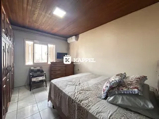 Quarto com cama grande, janela e forro de madeira.