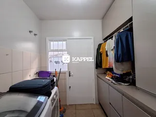 Foto de um ambiente interno mostrando uma área de serviço com máquina de lavar e armários.