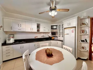 Foto de uma cozinha com armários brancos e bancadas escuras.