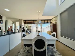Foto de uma sala de jantar ampla com mesa branca e iluminação clara.