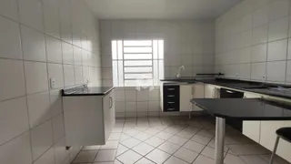Uma cozinha com piso de cerâmica e paredes brancas.
