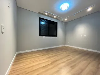 Sala de estar ampla com piso de madeira clara e iluminação moderna.