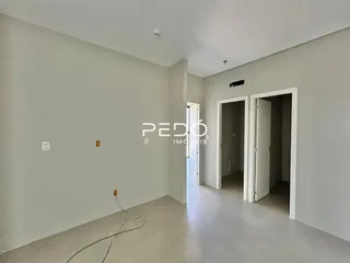 Hall de entrada com paredes brancas e piso claro.