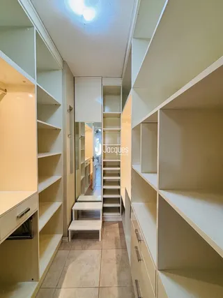 Hall de entrada com estantes embutidas e escada.
