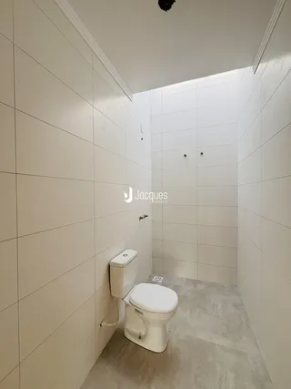 Foto de um banheiro com paredes brancas e piso claro.