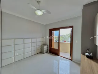 Quarto com paredes brancas e piso de cerâmica, com porta de vidro para varanda.