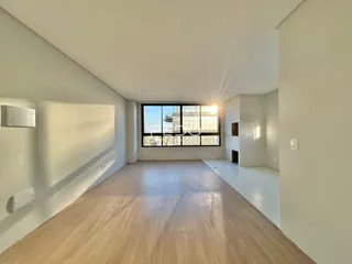 Sala de estar com piso de madeira clara e grande janela.