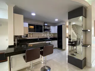 Vista da cozinha moderna com ilha e armários brancos.