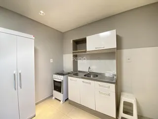 Cozinha com armários brancos e bancada de aço inoxidável.