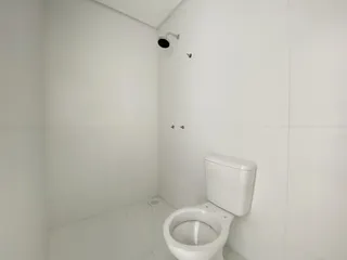 Banheiro com paredes brancas e piso de cerâmica.
