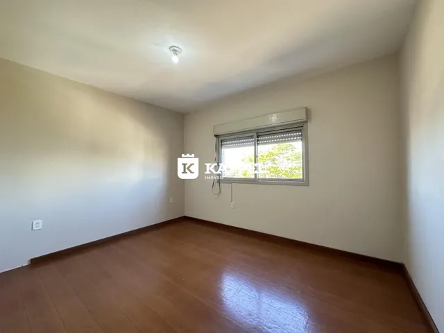 A sala de estar apresenta piso de madeira e uma janela com persianas.