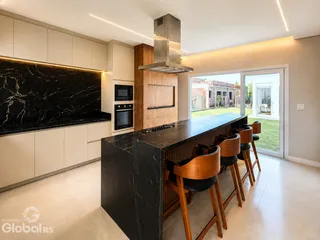 Vista de uma cozinha moderna com ilha de pedra escura e armários claros.