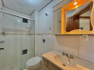 Foto de um banheiro com box de vidro e louças sanitárias.