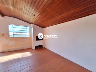 Sala com piso de cerâmica e forro de madeira exposto.