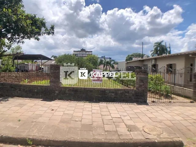 Vista externa de uma propriedade com muro de tijolos e vegetação no jardim.