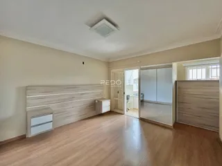 Ambiente interno de uma sala com piso de madeira clara e painel de madeira na parede.