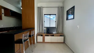 Ambiente interno com bancada escura, armários de madeira e uma janela grande.
