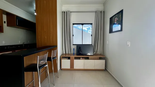 Ambiente interno com bancada escura, armários de madeira e uma janela grande.