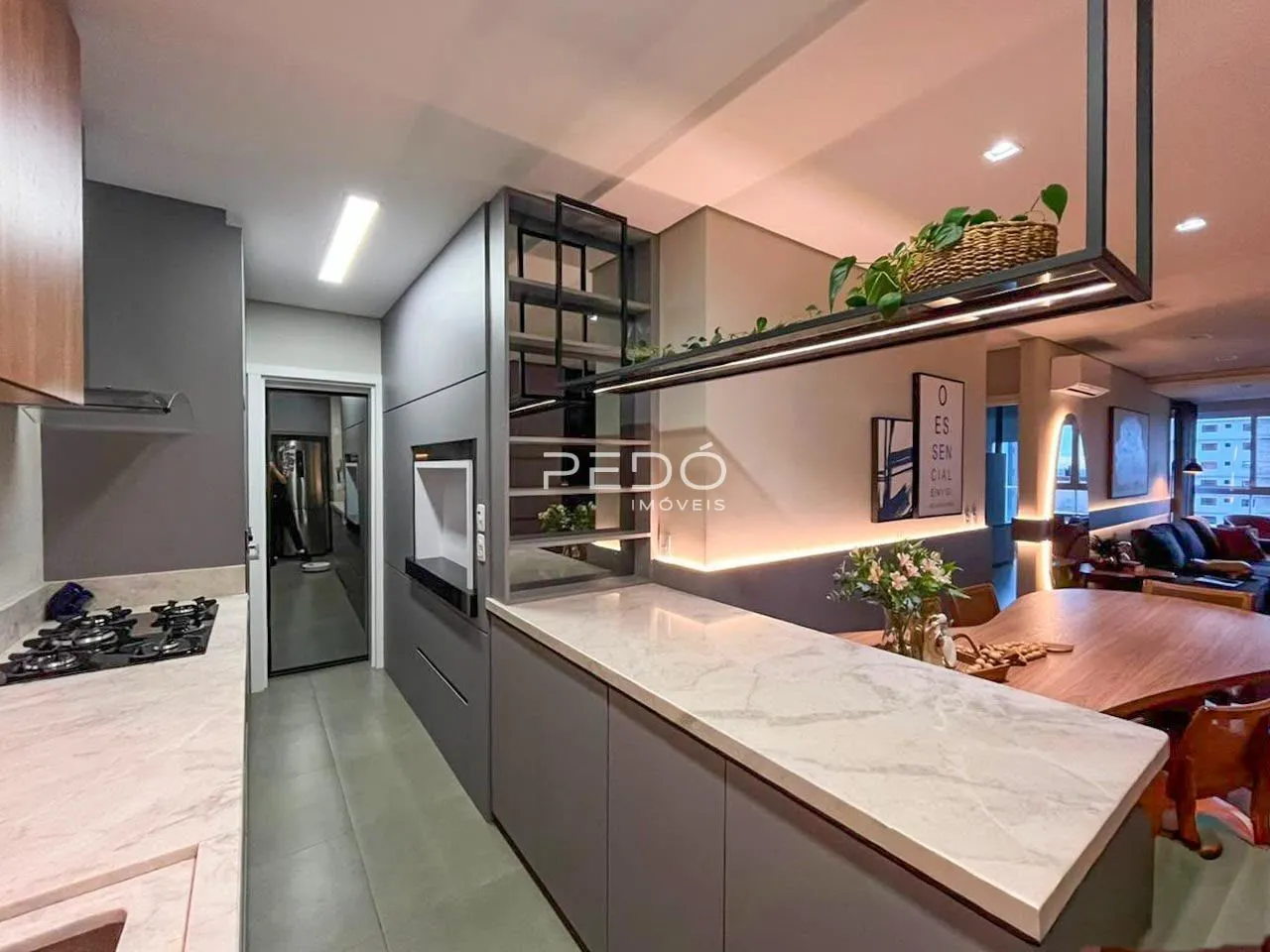 Sala de estar com cozinha integrada e mesa de jantar em um apartamento.