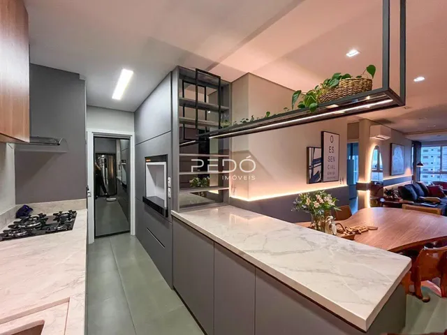 Sala de estar com cozinha integrada e mesa de jantar em um apartamento.