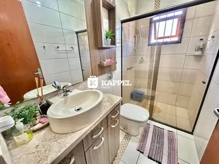 Banheiro com bancada de mármore e box de vidro transparente.