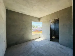 Interior de um cômodo com paredes de concreto aparente e um vão de luz.
