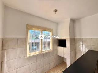 Foto de um corredor com paredes de azulejos claros e uma janela.