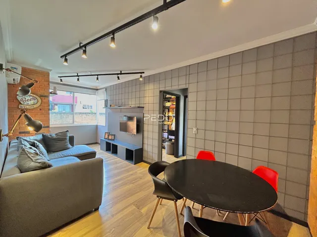 Sala de estar com sofá, mesa de jantar e piso de madeira.