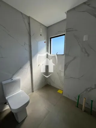 Foto do interior de um banheiro com paredes brancas e detalhes em mármore cinza.