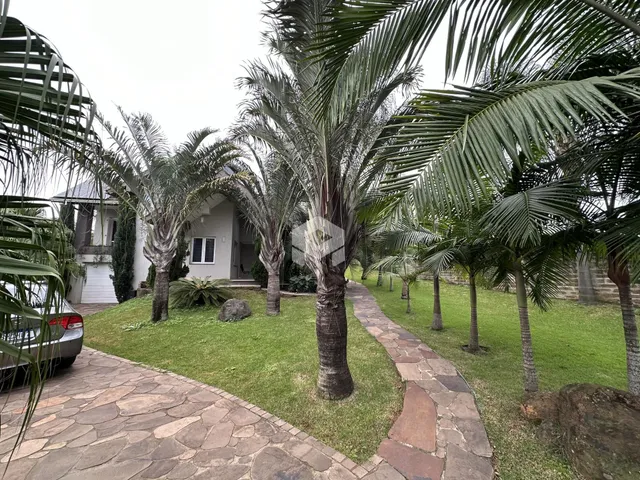 Vista externa de uma propriedade com paisagismo e palmeiras.