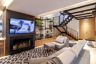 Sala de estar moderna com lareira e escadaria em um apartamento.