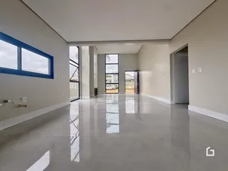 Ambiente interno amplo com piso claro e paredes brancas em uma residência.