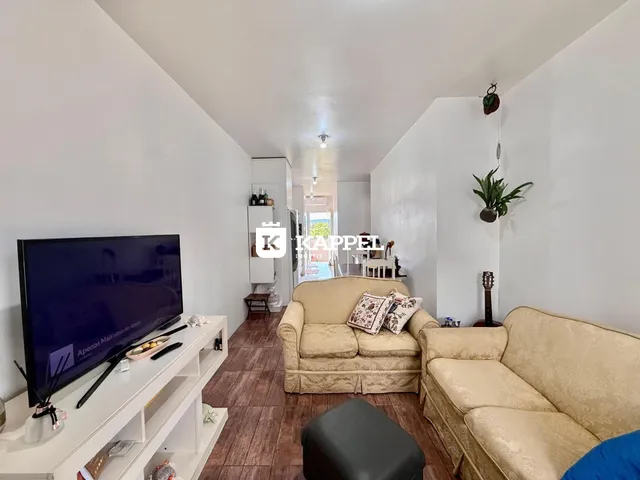 A sala de estar apresenta um sofá e uma televisão em um corredor.