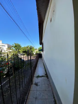 Vista lateral da fachada de uma residência com cerca e calçada.