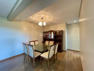 Foto de uma sala de jantar com mesa de vidro e cadeiras de madeira.