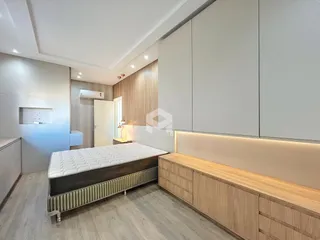 Quarto moderno com cabeceira e armários em madeira clara.