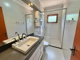 Interior de um banheiro moderno com bancada dupla e box de vidro.